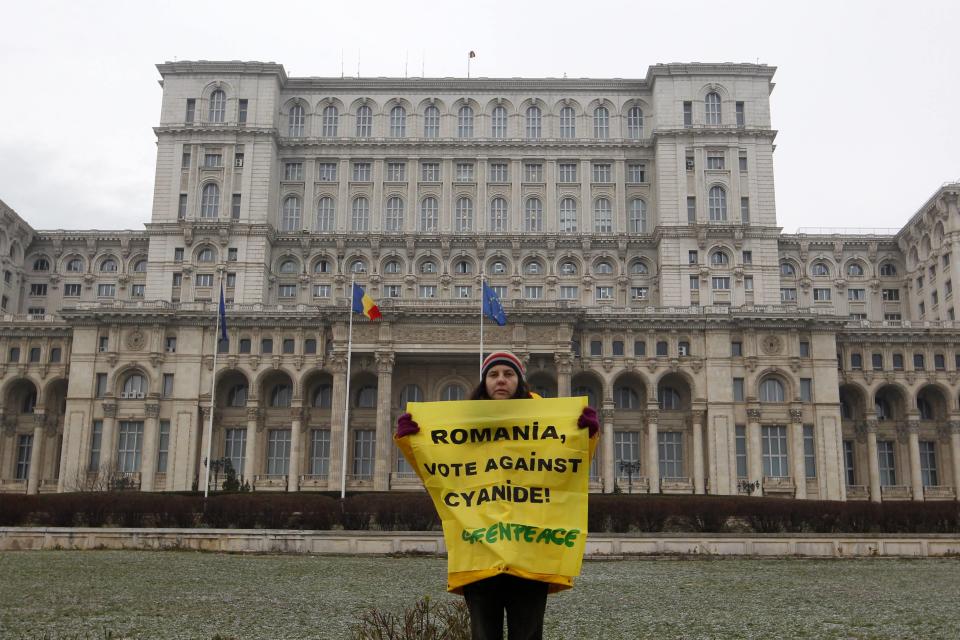 A Greenpeace activist holds a banner in the yard of Romania's Parliament in Bucharest