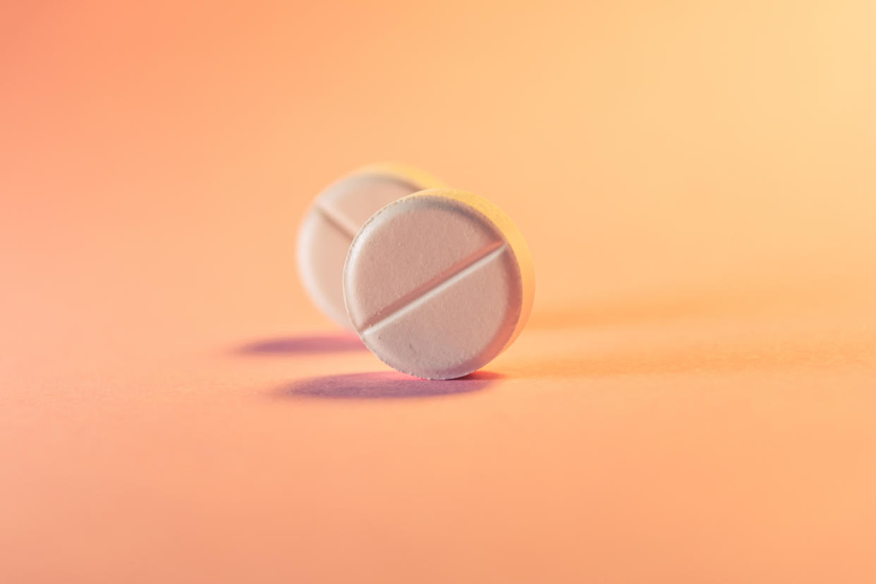 Two abortion pills in an orange-pink background. Medical theme. Selective focus.