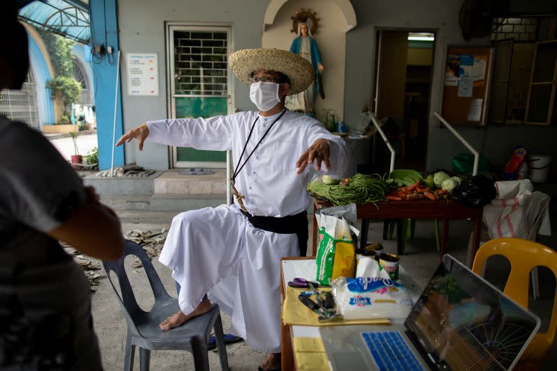 The Wider Image: Hazmat suits and holy water: two priests bring faith to Philippines lockdown