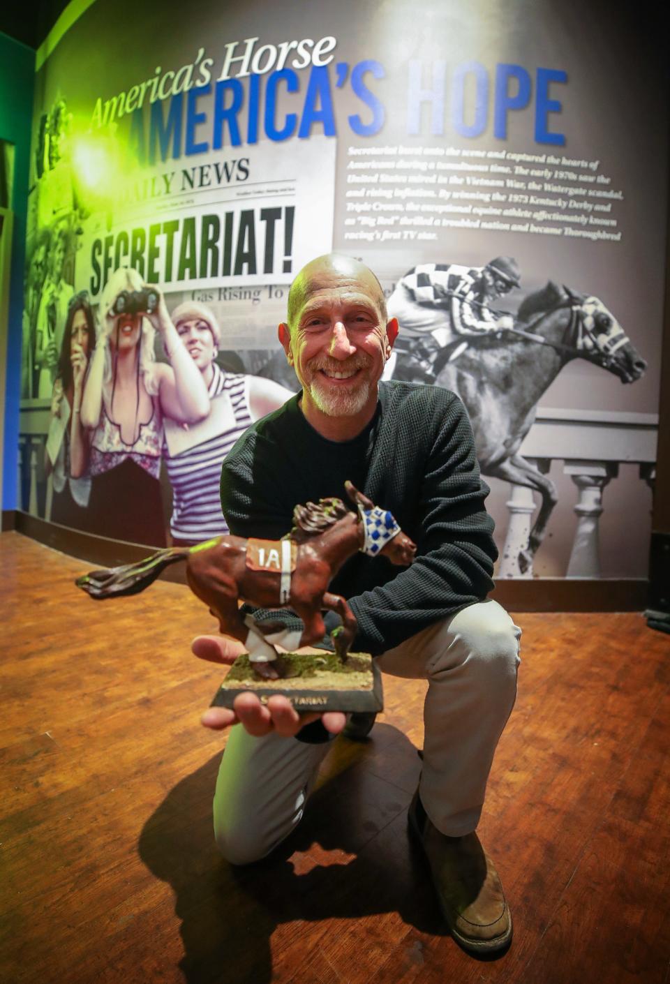 Leonard Lusky poses in the Secretariat exhibit at the Kentucky Derby Museum on Thursday, April 6, 2023.  He helped to develop and bring to market the Secretariat bobblehead the he is posing with.