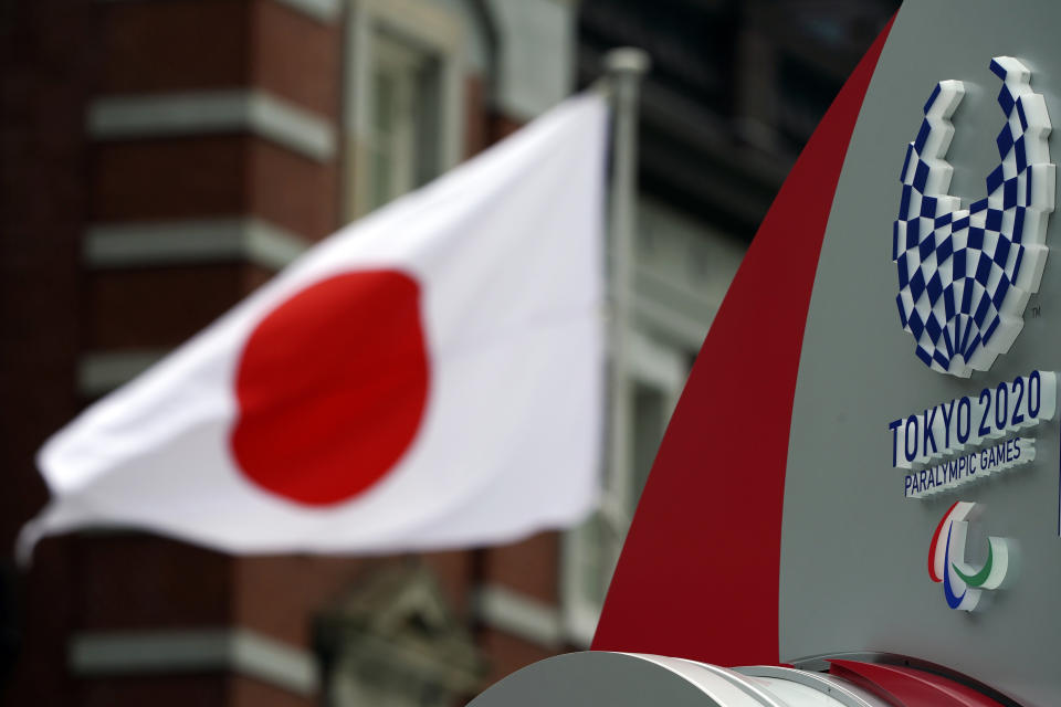 A Japanese flag is seen near Tokyo 2020 Paralympic logo at Tokyo Station in Tokyo Tuesday, April 21, 2020. An open conflict broke out Tuesday between Tokyo Olympic organizers and the IOC over how much to divulge about who will pay for the unprecedented year-long postponement. (AP Photo/Eugene Hoshiko)