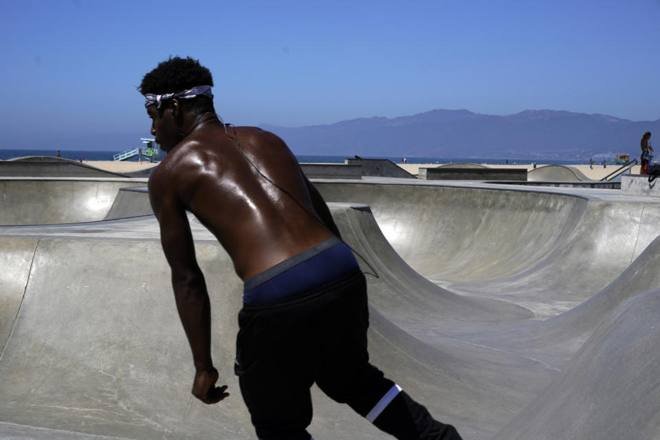 A shirtless skateboarder sweats amid triple digit temperatures in various parts of Southern California Wednesday, Aug. 31, 2022, in the Venice Beach section of Los Angeles. (AP Photo/Marcio Jose Sanchez)