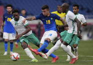 Brazil's Henrique Matheus, center, and Saudi Arabia's Abdulrahman Ghareeb, left, battle for the ball during a men's soccer match at the 2020 Summer Olympics, Wednesday, July 28, 2021, in Saitama, Japan. (AP Photo/Martin Mejia)