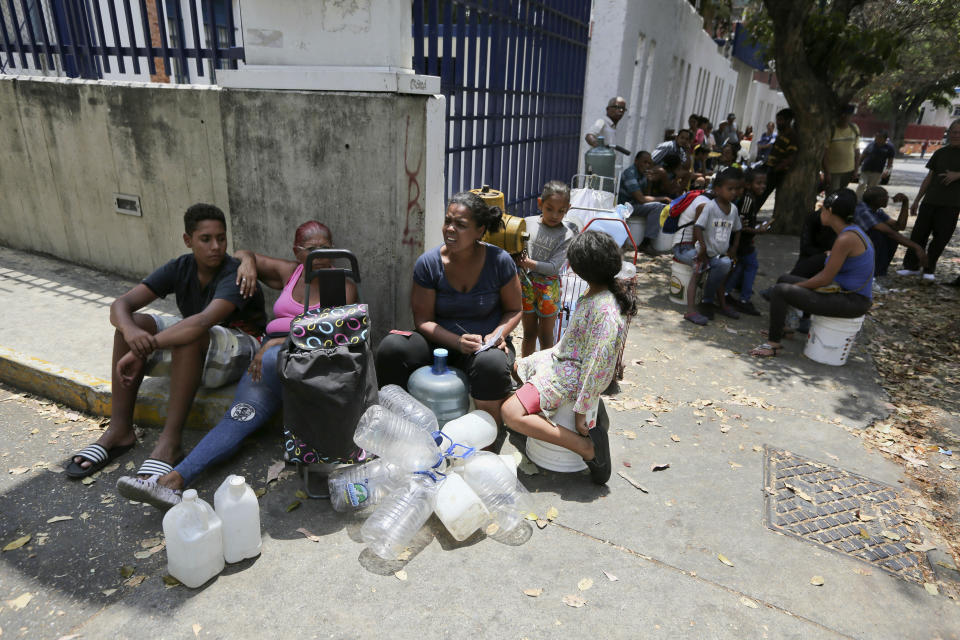 People wait their turn to fill containers with water from a public fountain in Caracas, Venezuela, Wednesday, March 13, 2019. Blackouts have marked another harsh blow to a country paralyzed by turmoil as the power struggle between Venezuelan President Nicolas Maduro and opposition leader Juan Guaido stretched into its second month. (AP Photo/Fernando Llano)