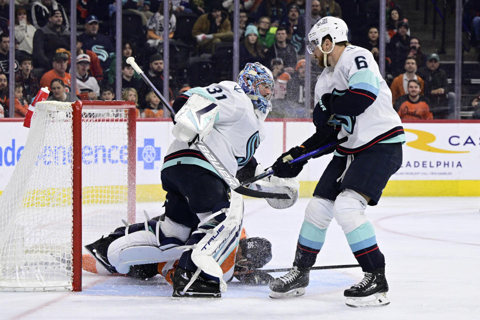 Philadelphia Flyers' Joel Farabee, bottom, crashes into Seattle Kraken goaltender Philipp Grubauer (31) as Kraken's Adam Larsson (6) defends during the second period an NHL hockey game, Sunday, Feb. 12, 2023, in Philadelphia. (AP Photo/Derik Hamilton)