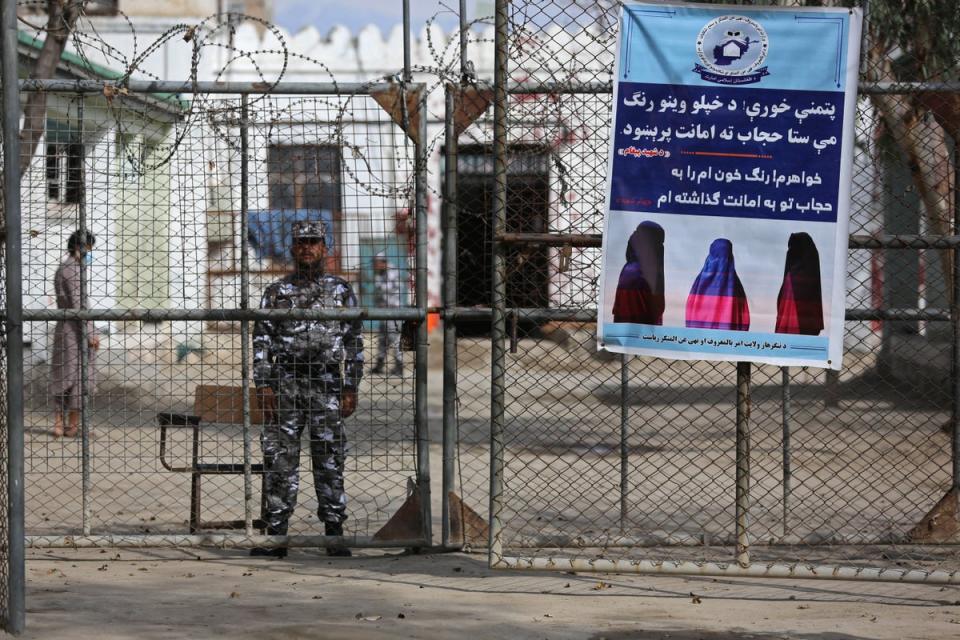 A Taliban security guard stands by a poster ordering women to wear Hijab, during a ceremony marking the distribution of new uniforms by the Taliban authorities at a prison in Jalalabad (AFP via Getty)