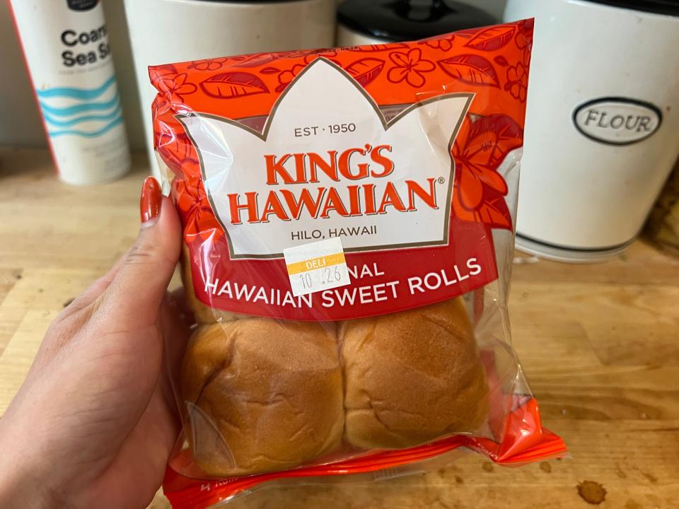 hand holding up a bag of kings hawaiian sweet rolls