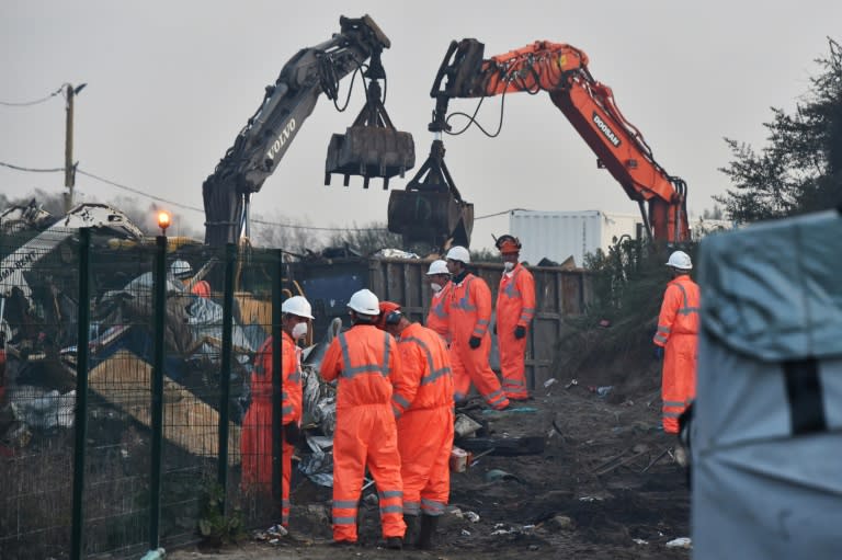 Members of the demolition crew stands by excavators tearing down the "Jungle" migrant camp in Calais, northern France during a massive operation to clear the squalid settlement