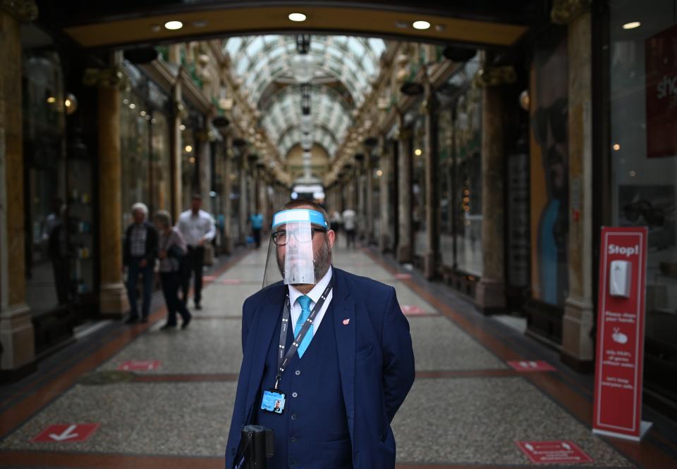 A member of staff stands at the entrance of the County Arcade wearing a PPE visor in the city centre of Leeds, on July 23, 2020, as England prepares to make the wearing of face coverings in shops mandatory as a new measure designed to combat the novel coronavirus COVID-19 pandemic. - The wearing of facemasks in shops in England will be compulsory from Friday, but full guidance is yet to be published. (Photo by Oli SCARFF / AFP) (Photo by OLI SCARFF/AFP via Getty Images)