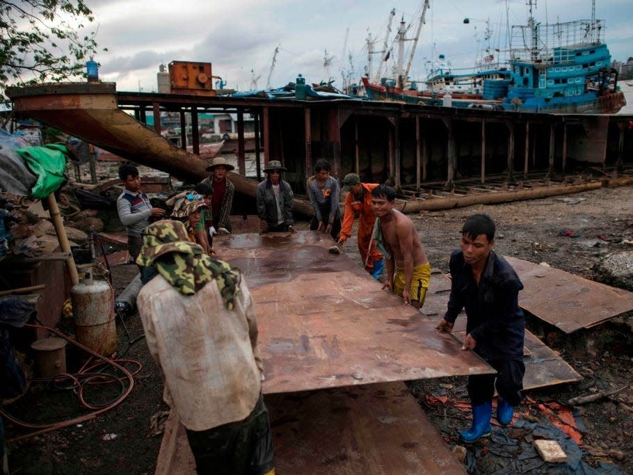 Workers carry a metal sheet dismantled from a ship at a ship-breaking yard on the bank of the Yangon River in Yangon on May 26, 2018.