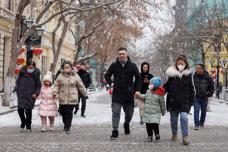 People walk with children in a pedestrian street in Harbin