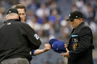 Third base umpire Bill Miller, left, and home plate umpire Brian Knight inspect the cap and glove of Kansas City Royals starting pitcher Brady Singer for foreign substances after Singer pitched the first inning of a baseball game against the New York Yankees, Tuesday, June 22, 2021, at Yankee Stadium in New York. (AP Photo/Kathy Willens)