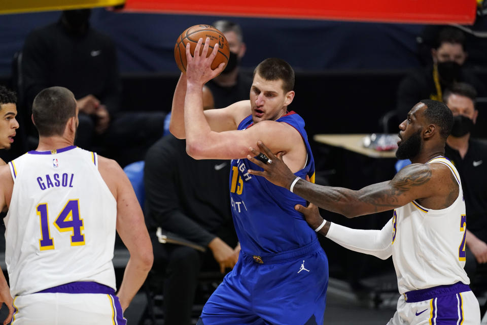 Denver Nuggets center Nikola Jokic, center, looks to pass the ball as Los Angeles Lakers center Marc Gasol, left, and forward LeBron James defend during the first half of an NBA basketball game Sunday, Feb. 14, 2021, in Denver. (AP Photo/David Zalubowski)