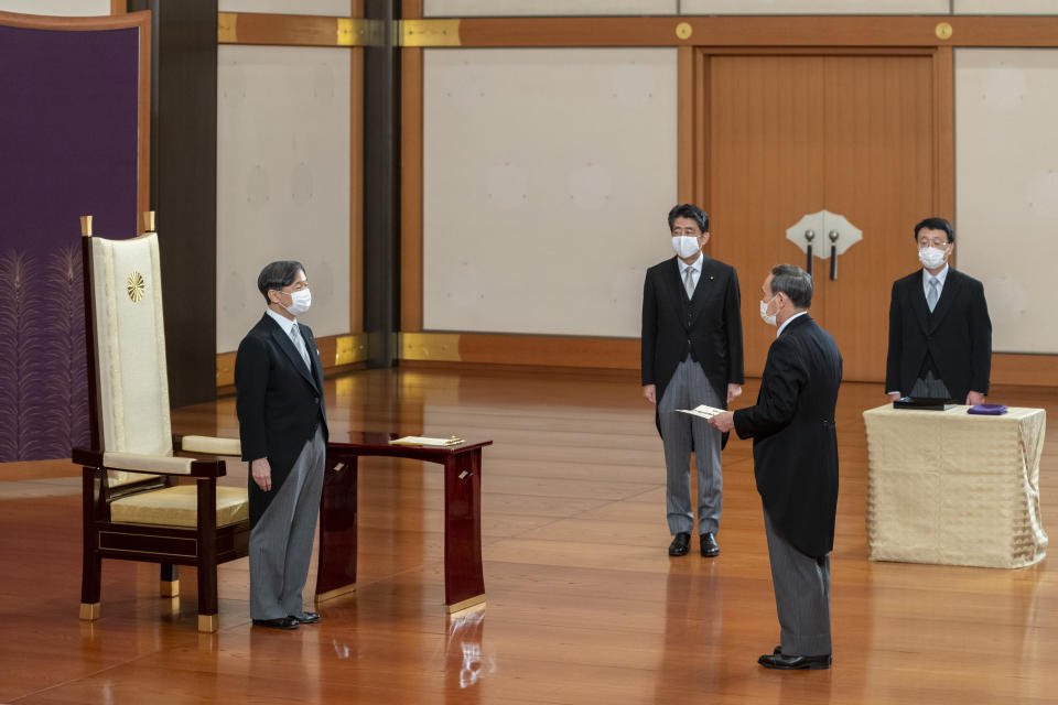 In this photo provided by the Imperial Household Agency of Japan, Emperor Naruhito, left, stands before Prime Minister-elect Yoshihide Suga, as Prime Minister Shinzo Abe, rear center, looks on during the attestation ceremony for Suga at the Imperial Palace in Tokyo Wednesday, Sept. 16, 2020.(The Imperial Household Agency of Japan via AP)