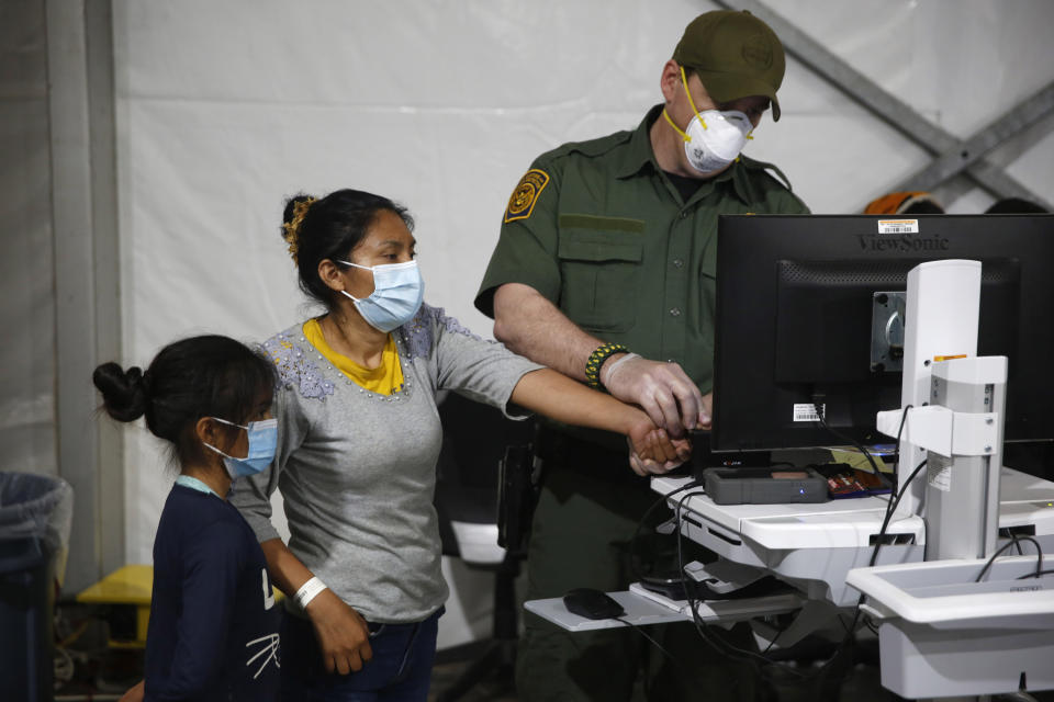 FILE - In this March 30, 2021, file photo, a migrant and her daughter have their biometric data entered at the intake area of the U.S. Department of Homeland Security holding facility, the main detention center for unaccompanied children in the Rio Grande Valley, in Donna, Texas. Migrant families will be held at hotels in the Phoenix area in response to a growing number of people crossing the U.S.-Mexico border, authorities said Friday, April 9, 2021 another step in the Biden administration's rush to set up temporary space for them. (AP Photo/Dario Lopez-Mills, Pool, File)