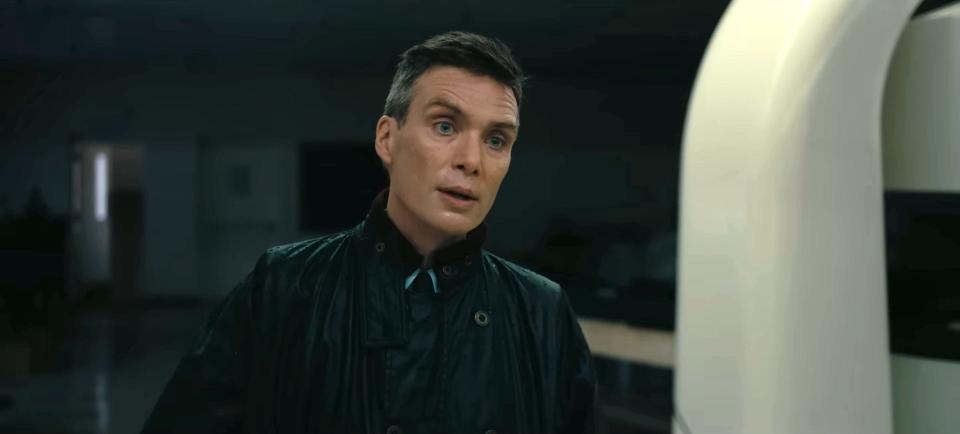 Cillian Murphy as J. Robert Oppenheimer, wearing a black raincoat.