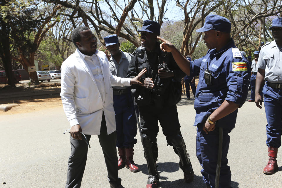 A Zimbabwean doctor is told to retreat after attempting to march in Harare, Wednesday, Sept, 18, 2019. Zimbabwean doctors protesting the alleged abduction of a union leader were met by a line of baton- wielding police in the capital as fears grow about government repression. (AP Photo/Tsvangirayi Mukwazhi)