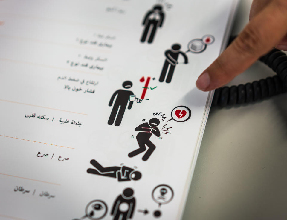 07 August 2019, Hessen, Offenbach: Internist Matthias Zimmer (37) explains in a treatment room at the Ketteler Hospital the use of a booklet showing illustrations and words for complaints in Arabic. The Malteser Hilfsdienst offers medical treatment for people without health insurance once a week, anonymously if desired. Photo: Frank Rumpenhorst/dpa (Photo by Frank Rumpenhorst/picture alliance via Getty Images)