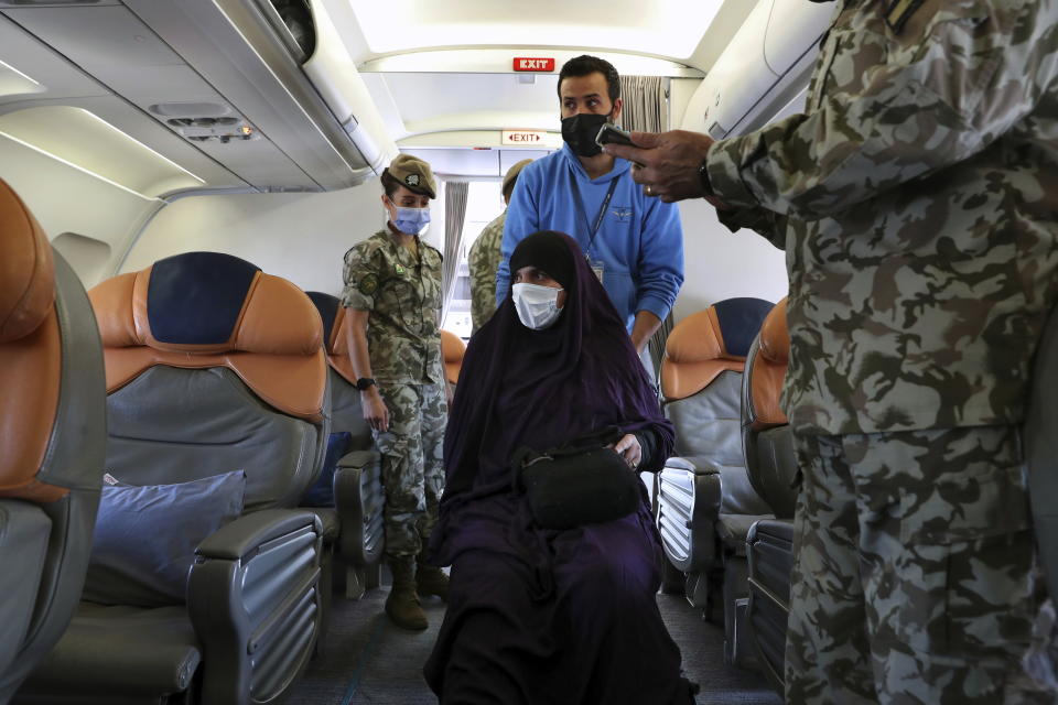 An Albanian woman, center, boards a plane, during an operation to take home five Albanians from al-Hol, northern Syria, in Beirut, Lebanon, Tuesday, Oct. 27, 2020. The repatriation of four children and a woman related to Albanian nationals who joined Islamic extremist groups in Syria "is a great step" to be followed by more repatriations, Albania's prime minister said Tuesday in Beirut. (AP Photo/Bilal Hussein)