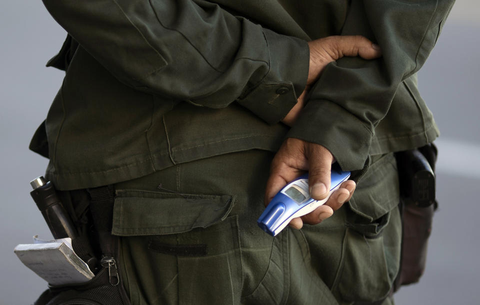 A municipal police officer holds a no-touch forehead thermometer at a checkpoint amid increased restrictions on residents' movements in an effort to curb the spread of the new coronavirus in Niteroi, Brazil, Monday, May 11, 2020. (AP Photo/Silvia Izquierdo)