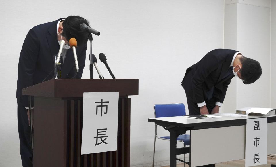 Susono Mayor Harukaze Murata, left, and vice mayor, right, bow during a press conference at the city hall in Susono, Shizuoka Prefecture, central Japan, Monday, Dec. 5, 2022. Japanese police said Monday that they have arrested three teachers at a nursery school in central Japan on suspicion they routinely abused toddlers, such as hitting their heads, holding them upside down and locking them up in a bathroom, a case that triggered outrage across the nation. (Kyodo News via AP)