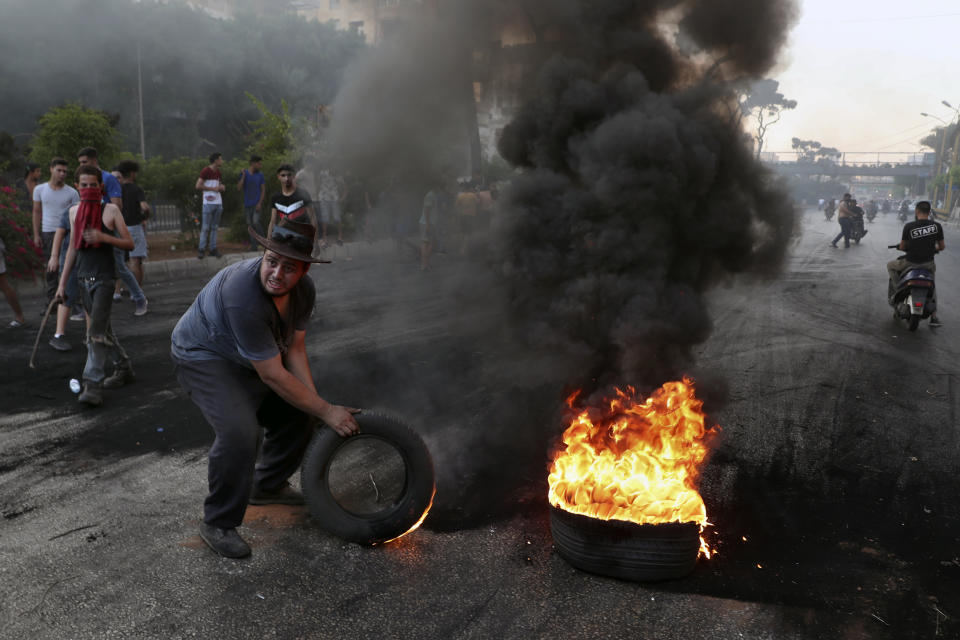 Protesters burn tires to block a road, in Beirut, Lebanon, Thursday, June 24, 2021. Dozens of angry protesters, angered by deteriorating living conditions and government inaction, partially blocked Beirut's main highway to the capital's only airport, turning trash bin over and setting tires on fire. (AP Photo/Bilal Hussein)