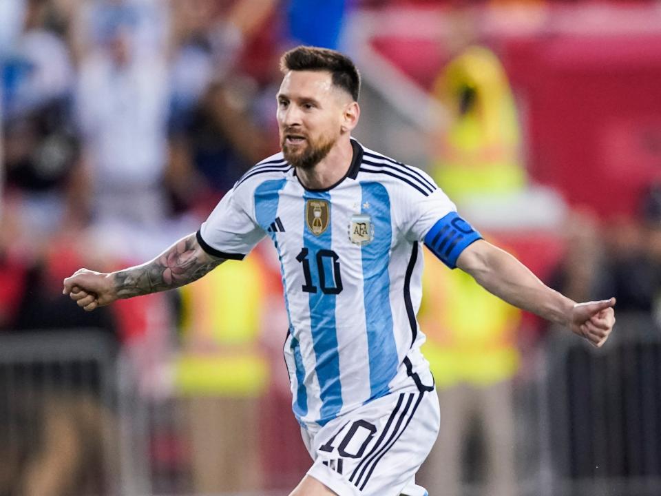 Lionel Messi runs with his arms out to sides in celebration during an Argentina soccer match.