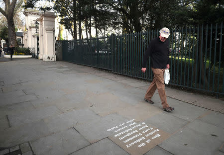 A man walks past graffiti sprayed on the pavement near the entrance to the Russian embassy and ambassador's residence in London, Britain, March 15, 2018. REUTERS/Hannah McKay