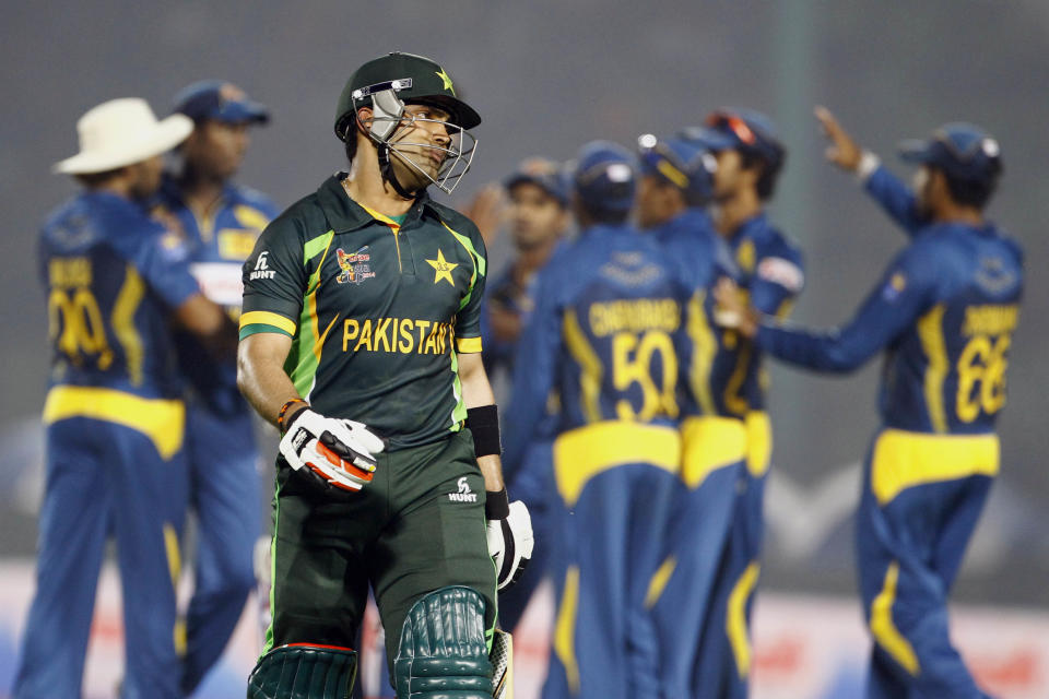 Pakistan’s Umar Akmal, foreground, walks back to the pavilion after his dismissal by Sri Lanka’s Suranga Lakmal during the opening match of the Asia Cup one-day international cricket tournament between them in Fatullah, near Dhaka, Bangladesh, Tuesday, Feb. 25, 2014. (AP Photo/A.M. Ahad)