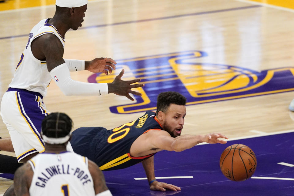 Golden State Warriors guard Stephen Curry, right, dives for a loose ball while Los Angeles Lakers guard Dennis Schroder, left, and guard Kentavious Caldwell-Pope watch during the first half of an NBA basketball game Sunday, Feb. 28, 2021, in Los Angeles. (AP Photo/Mark J. Terrill)
