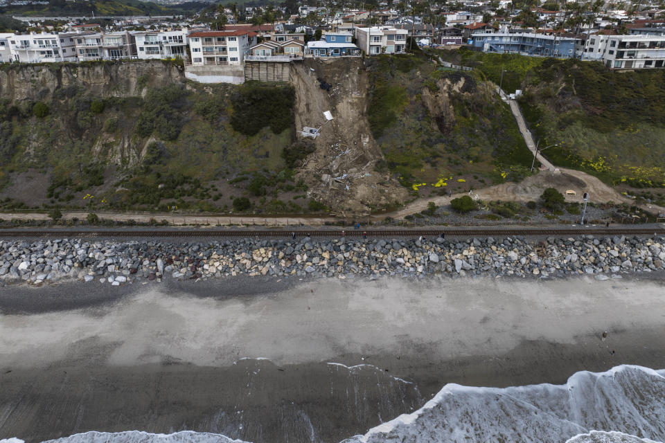 In this image taken with a drone, a mass of debris is seen along a cliff beneath residential homes after a landslide occurred in San Clemente, Calif., Thursday, March 16, 2023. (AP Photo/Jae C. Hong)