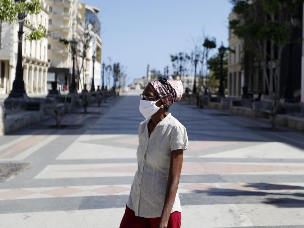 A woman wearing face mask walks along empty Paseo del Prado as protective measures against coronavirus (Covid-19) pandemic are taken in Havana, Cuba (Anadolu/Getty)