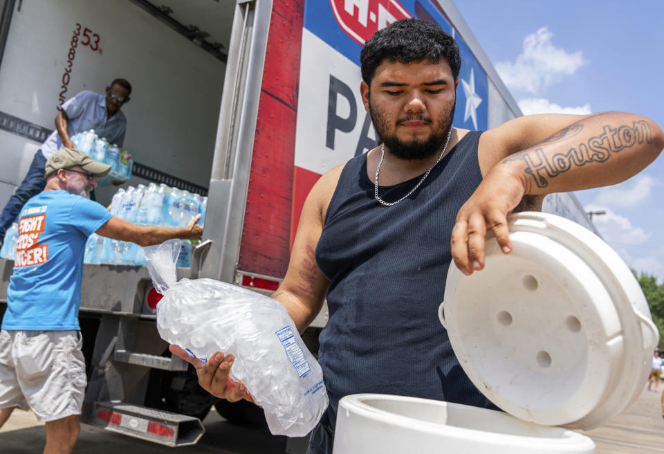Daniel Valdez places a fresh bag of ice in a cooler his brought on foot from his apartment as volunteers at the Memorial Assistance Ministries distributed water and ice, Saturday, May 18, 2024, in Houston. As of Saturday afternoon, 486,000 people in the Houston area remained without power after a Thursday's thunderstorms killed at least seven people. (Jason Fochtman/Houston Chronicle via AP)