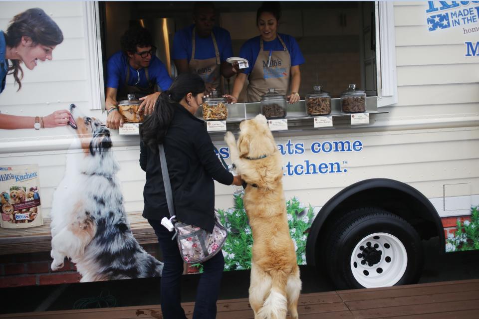 Tiffany Day (L), reacts as her dog Ziggy, a one-year-old Golden Retriever stands to check out a selection of free dog treats at Milo's Kitchen Treat Truck in San Francisco, California June 27, 2014. Milo's Kitchen, a San Francisco-based pet food company, on Friday started its nationwide food truck tour specifically catered to dogs. REUTERS/Stephen Lam (UNITED STATES - Tags: BUSINESS ANIMALS)