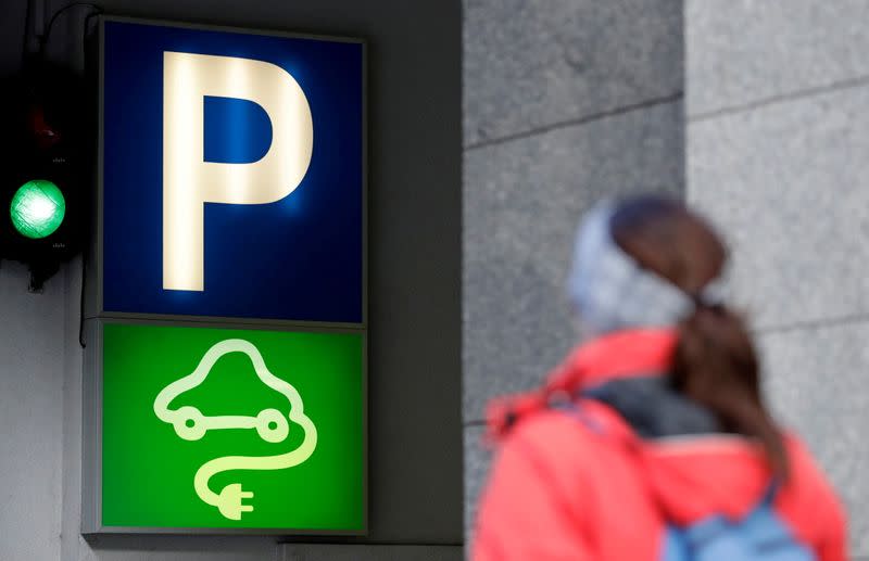 FILE PHOTO: A woman walks past a sign of a charging point for electric vehicles in Prague