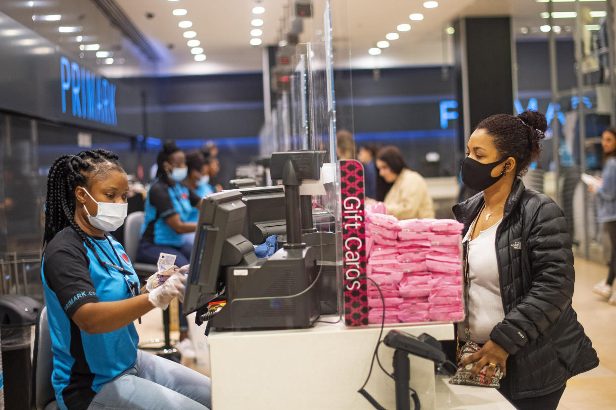 A staff member and customer wear face masks, with a protective screen at the till point, inside Primark in Oxford Street, London as non-essential shops in England open their doors to customers for the first time since coronavirus lockdown restrictions were imposed in March.