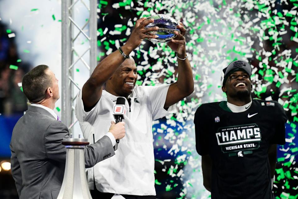Head coach Mel Tucker of the Michigan State Spartans holds the championship trophy after defeating the Pittsburgh Panthers during the Chick-Fil-A Peach Bowl at Mercedes-Benz Stadium on December 30, 2021 in Atlanta, Georgia.