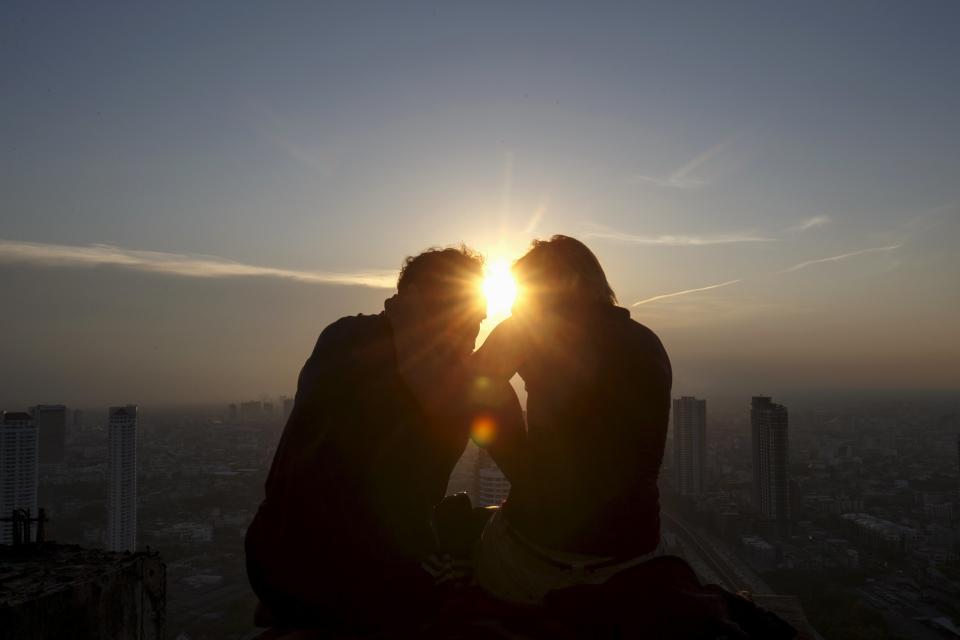 A couple enjoy the sunset on the roof top of an abandoned building in Bangkok