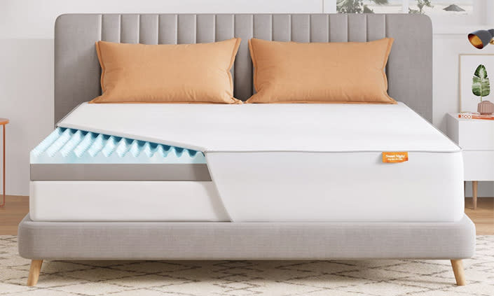 gray bed with mattress and tan pillows