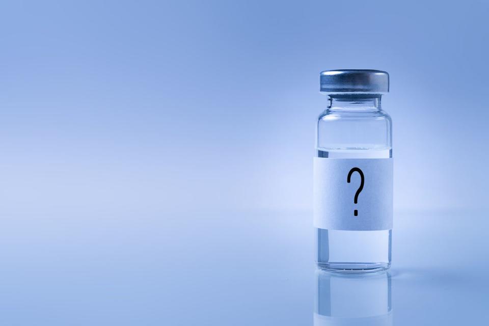 a glass medical bottle with a question mark on the label an ampoule with a vaccine for covid 19 or for colds and flu on a white background the concept of treatment and prevention of the spread of infection, virus and pneumonia