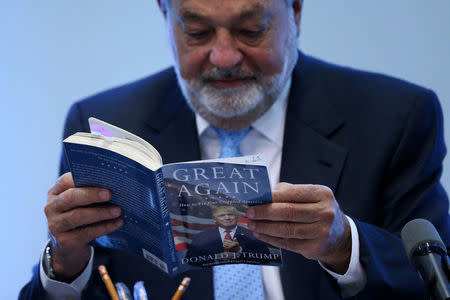 Mexican billionaire Carlos Slim reads the book "Crippled America: How to make America great again" by Donald Trump during a news conference in Mexico City, Mexico, January 27, 2017. REUTERS/Edgard Garrido