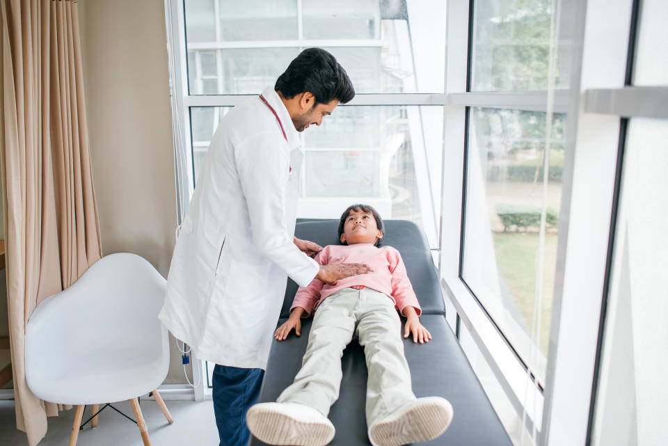 A doctor examines a child lying on an examination table in a medical setting