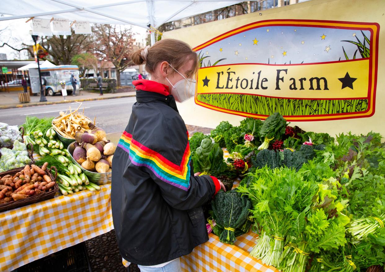 Laura Palmer works at her family's produce L'Etoile Farm stand at the Winter Farmers Market in Eugene on opening day in February 2021.