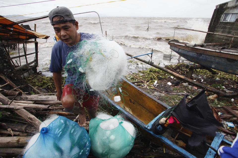 A fisherman carries net after making it safely back to shore in fishing village after strong winds from Typhoon Haiyan battered Bayog town in Los Banos, Laguna city