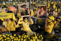 Supporters of Thai monarch display images of the late King Bhumibol Adulyadej ahead of the arrival of King Maha Vajiralongkorn and Queen Suthida to participate in a candle lighting ceremony to mark birth anniversary of late King Bhumibol Adulyadej at Sanam Luang ceremonial ground in Bangkok, Thailand, Saturday, Dec. 5, 2020. (AP Photo/Gemunu Amarasinghe)