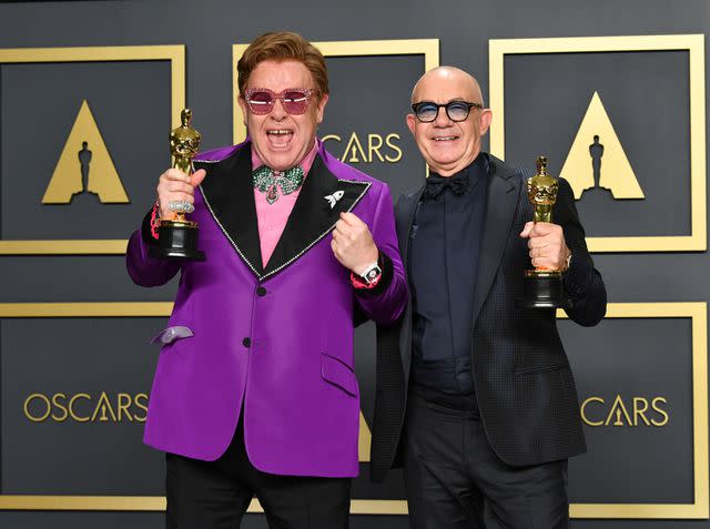 <p>Amy Sussman/Getty</p> Elton John and Bernie Taupin hold their Best Original Song Oscars in February 2020