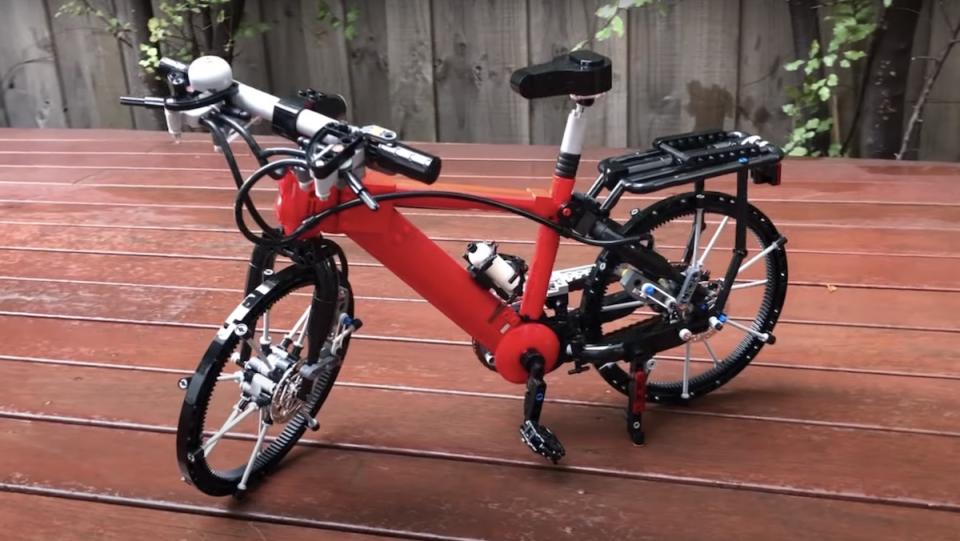 A miniature red bicycle made of LEGO pieces standing on a picnic table