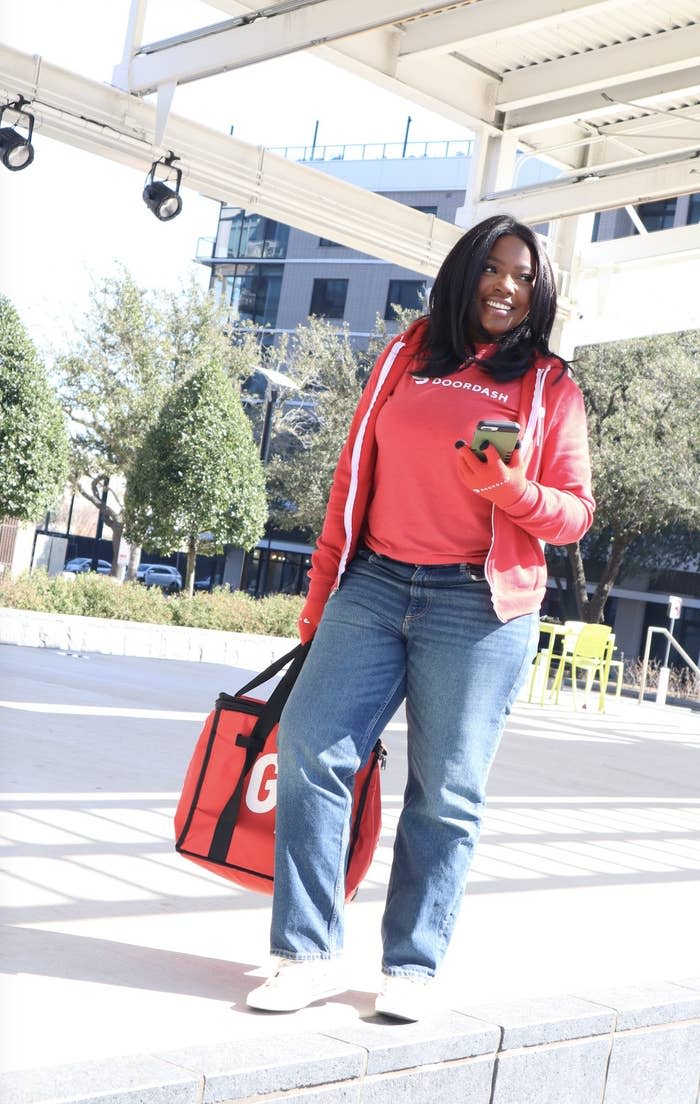 Women smiling with Door Dash Shirt holding cell phone