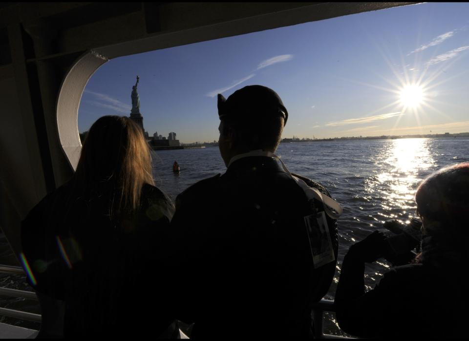 A couple of new citizens hug as they take the ferry to attend a naturalization ceremony on Liberty Island in New York on October 28, 2011 to commemorate the 125th anniversary of the dedication of the Statue of Liberty.   AFP PHOTO / TIMOTHY A. CLARY (Photo credit should read TIMOTHY A. CLARY/AFP/Getty Images)