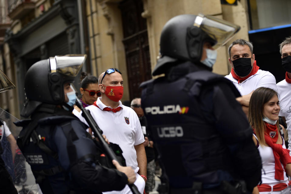 Residents, wearing white clothes and traditional red scarves, take to the streets on the day the ''txupinazo'' would usually take place to start the famous San Fermin festival, which was due canceled this year by the conoravirus, in Pamplona, northern Spain, Monday, July 6, 2020. (AP Photo/Alvaro Barrientos)